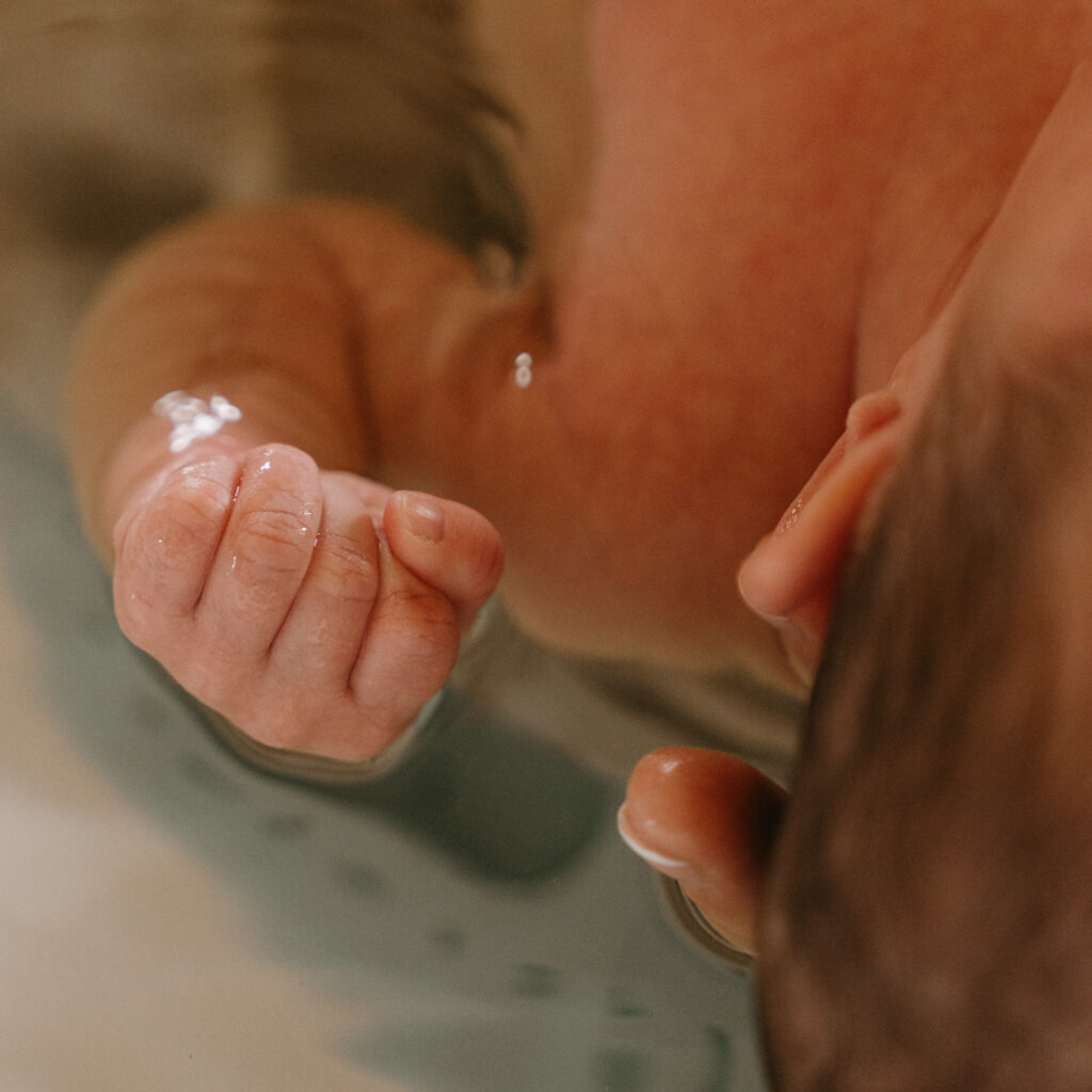Détail main d'un bébé dans une bain bébé