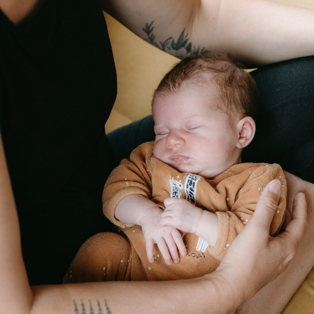 Image d'un bébé qui dort dans les bras de sa maman